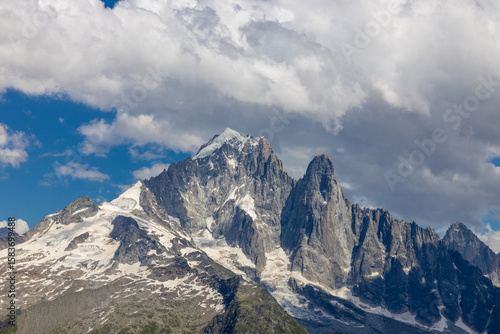 Beautiful mountain landscapes of the Alps on Tour du Montblanc hike. Green valley, snow summits and rocky peaks of Aiguilles de Chamonix and Montblanc. Summer sunny weather blue sky, trekking Alp hike