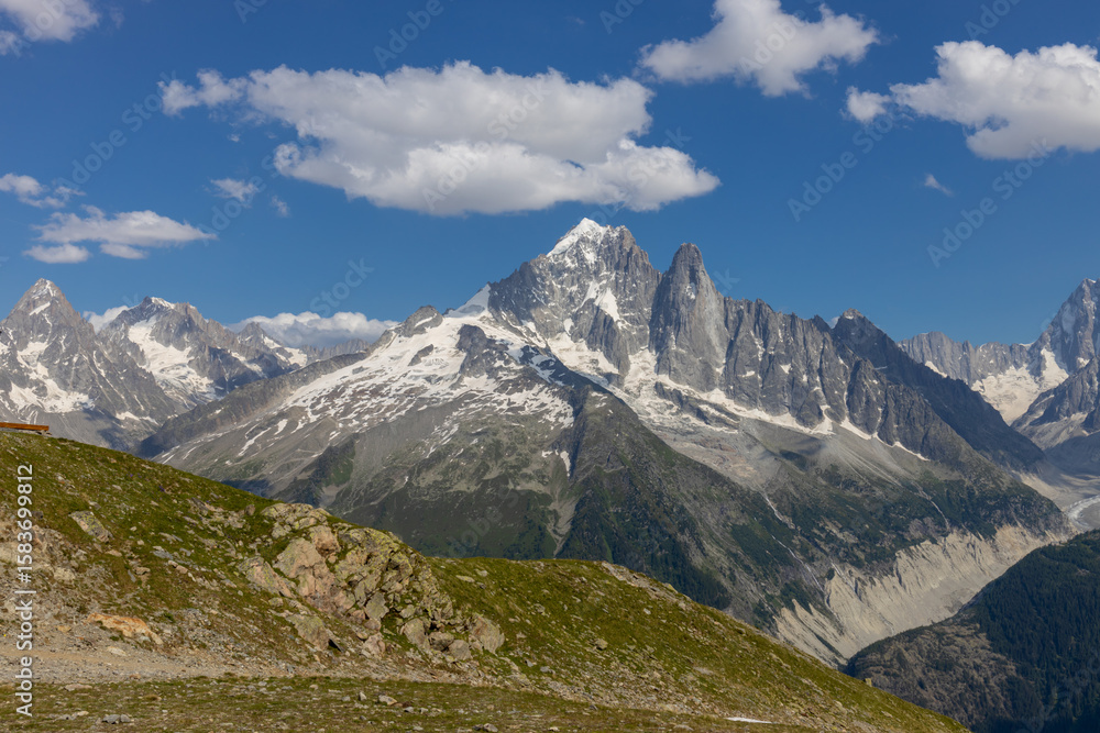 Fototapeta premium Beautiful mountain landscapes of the Alps on Tour du Montblanc hike. Green valley, snow summits and rocky peaks of Aiguilles de Chamonix and Montblanc. Summer sunny weather blue sky, trekking Alp hike