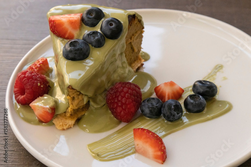 Delicious cake slice with matcha glaze and fresh berries