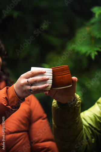 Handmade pottery mug cheers with warm drink in forest setting