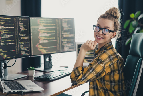 Obraz na plátně Young female programmer working on coding projects in a modern home office with dual monitors and a creative workspace