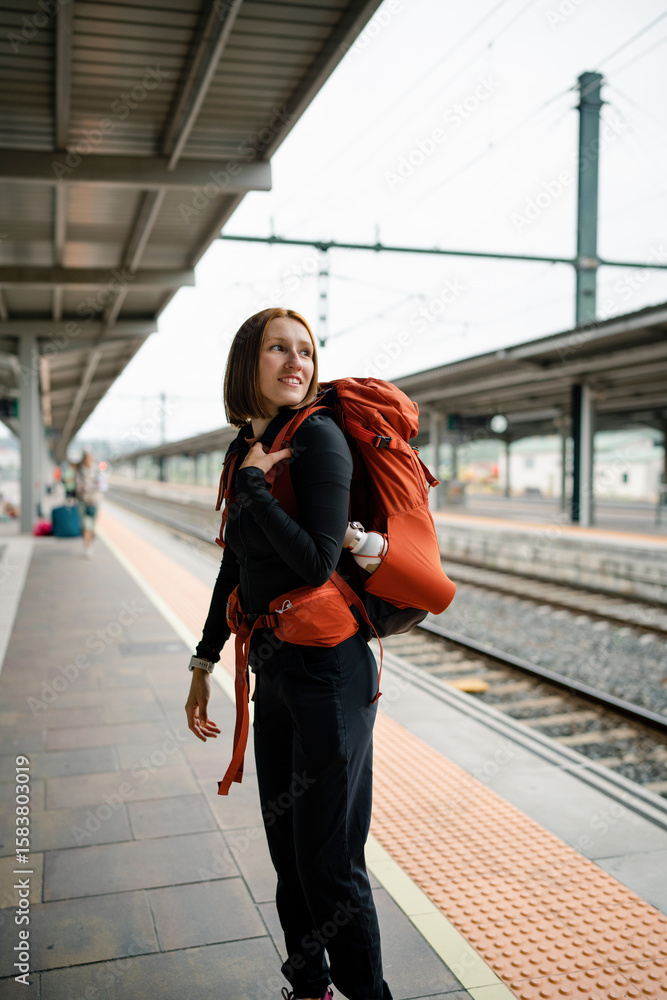Obraz premium Young backpacker woman waiting at train station