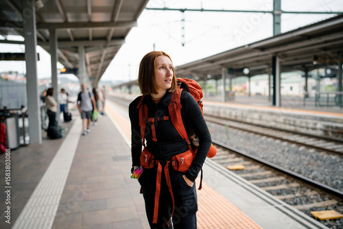 Young backpacker woman waiting at train station platform