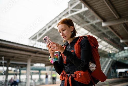 Young backpacker using smartphone at train station
