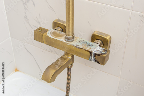 Plaque from hard water on gold shower faucet. Streaks or rust. Blue calcareous plaque
