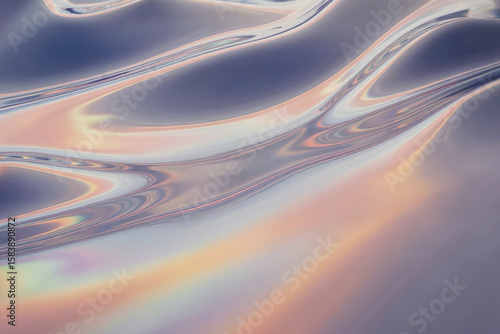 A close-up macro photograph of iridescent holographic material showing flowing, wavy patterns. The surface displays a gradient of colors including deep blues, soft pinks, and metallic silvers.