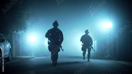 Silhouetted soldiers advance through a foggy street illuminated by blue lights during nighttime operations