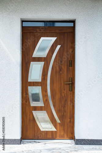 Inviting front entrance with a grand wooden door, stone accents, and decorative plants displayed. Facade of a modern building with modern doors. Designer entrance door to country house. Modern design.