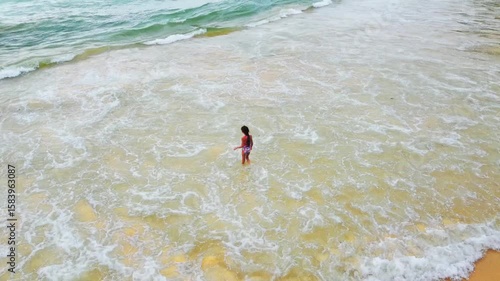 Little girl plays with the sea and jumps on the waves at Naithon Beach, Phuket