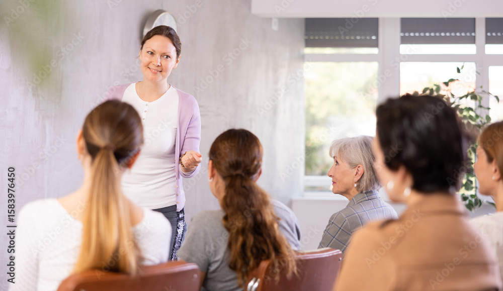 Fototapeta premium Young female teacher giving lecture to group of students in classroom