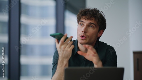 Tableau sur toile Freelancer dictating voice message at smartphone sitting agency office closeup