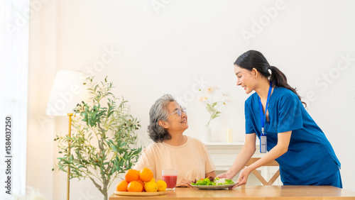 Female caregiver take care and serving healthy food organic salad to senior woman at nursing home. Retirement rehabilitation. Elderly people health, home medical wellness healthcare services concept.