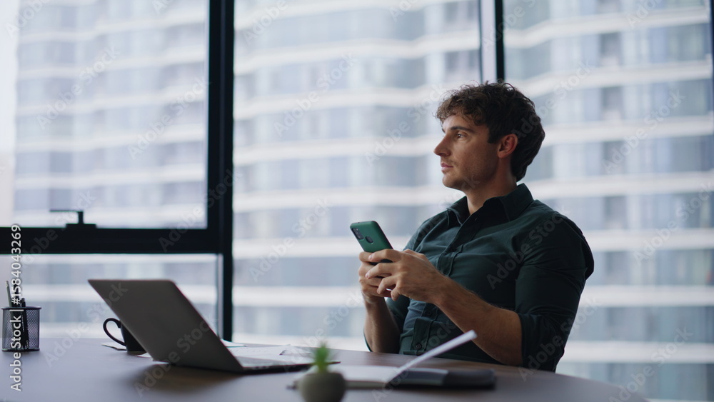 Fototapeta premium Stylish ceo reading cellphone message in modern office. Smiling businessman