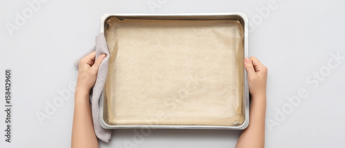 Schilderij op canvas Woman holding baking tray with paper on grey background, closeup