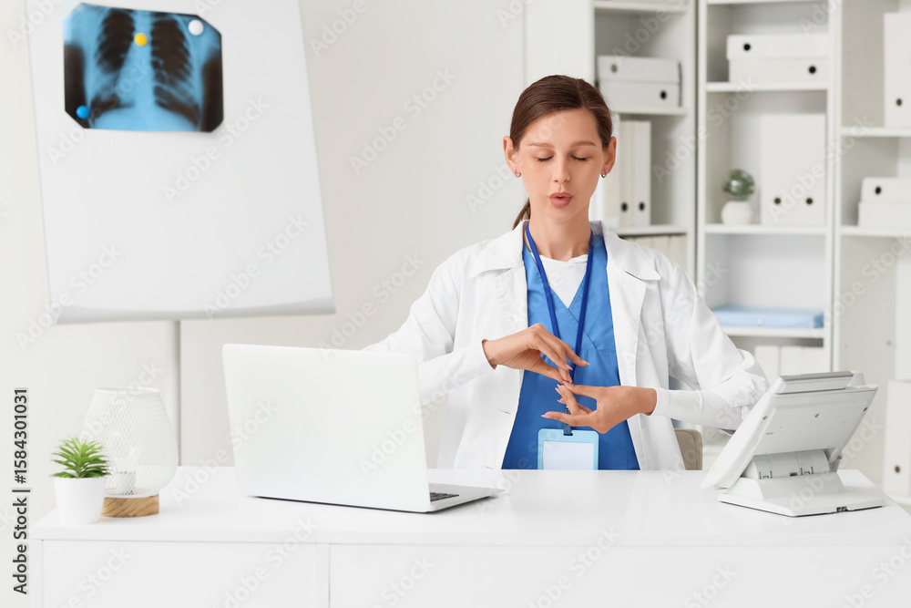 Female doctor meditating at table in clinic Female doctor meditating at table in clinic