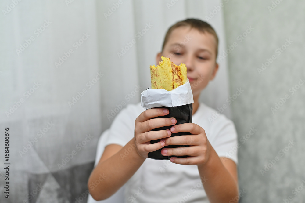 delicious shawarma in the hands of a boy. He is happy and looks at her with great appetite. delicious shawarma in the hands of a boy. He is happy and looks at her with great appetite.