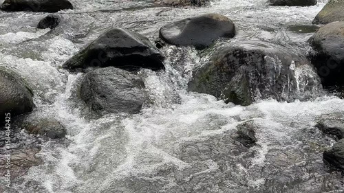 Clear mountain river water flows swiftly between large rocks, top view. Clear mountain river water. The water flows in waves. Splash of river water. Natural river views in the countryside.