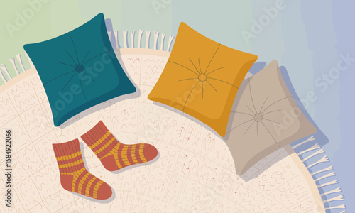 Top-down view of three colorful pillows and striped socks arranged on a round rug with fringe, creating a cozy and inviting scene.