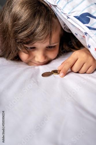 Wall Mural Child girl discovering coins under pillow.