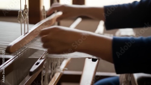 Hands weaving fabric on traditional loom close up view of textile production