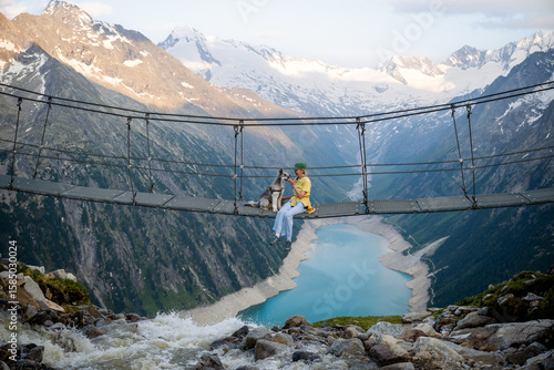 Woman sitting on suspension bridge with her dog in the Austrian Alps