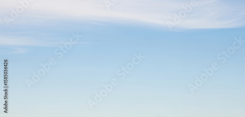Fototapeta Naklejka Na Ścianę i Meble -  Light blue sky with a few wispy clouds drifting high above, creating an airy and open atmosphere suitable for minimalist backgrounds or serene design compositions.