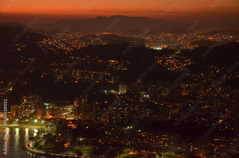 Obraz premium Sunset at night on Rio de Janeiro with city lights and the sea and the mountains