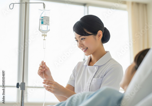 患者に点滴を行なう白衣の日本人女性看護師