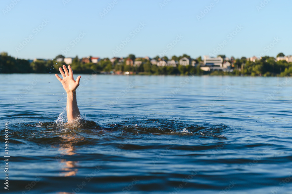 Fototapeta premium Man drowning in water, reaching for help near city