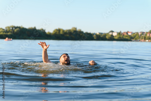 Obraz na plátně Man drowning in lake is raising hand asking for help