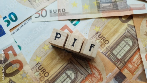 PIF acronym made of wooden letter cubes on pile of Euro banknotes. Piano di Investimento Fondi (Investment Fund Plan)