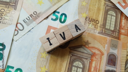 IVA acronym made of wooden letter cubes on pile of Euro banknotes. Imposta sul Valore Aggiunto (Value Added Tax)