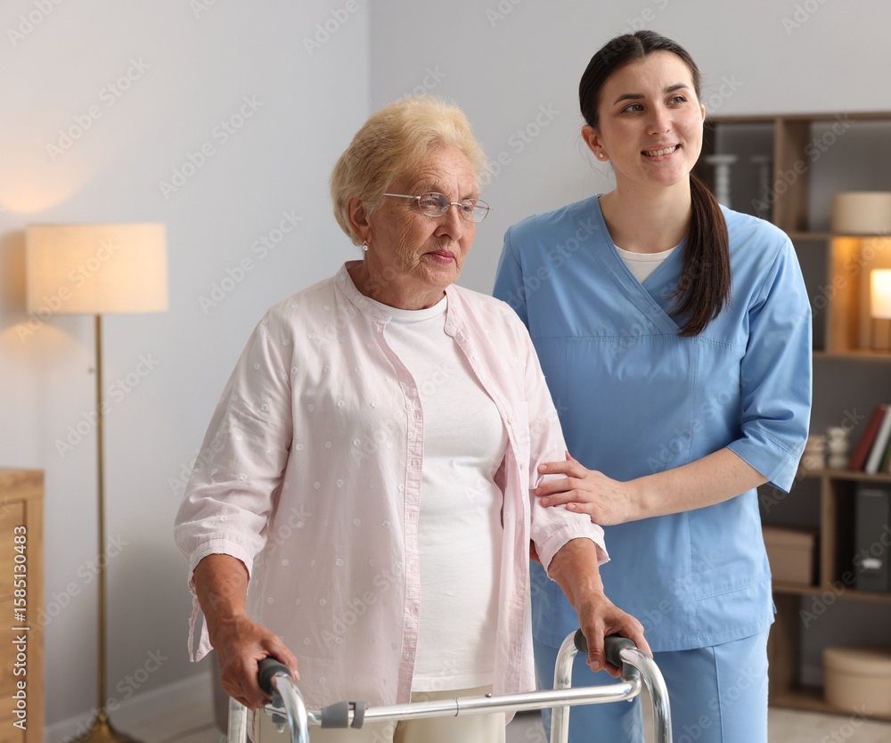 Obraz premium Nurse assisting senior woman with walking frame indoors. Home health care service