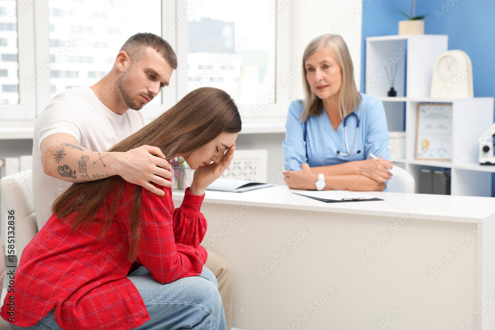 Fototapeta premium In vitro fertilization (IVF). Upset couple having consultation with doctor in reproductive clinic