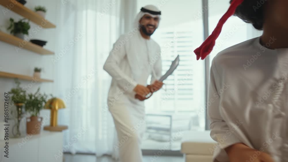Happy arab dad in traditional kandura and his son dressed as a pirate are enjoying their time together, pretending to sword fight with inflatable toys in their modern living room Happy arab dad in traditional kandura and his son dressed as a pirate are enjoying their time together, pretending to sword fight with inflatable toys in their modern living room