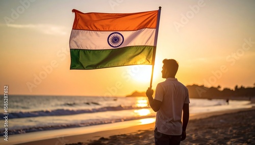 Silhouette of a person holding the Indian flag against a setting sun on a beach