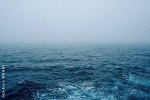 A misty, overcast day at sea.  Dark blue water with small waves stretches to a hazy horizon