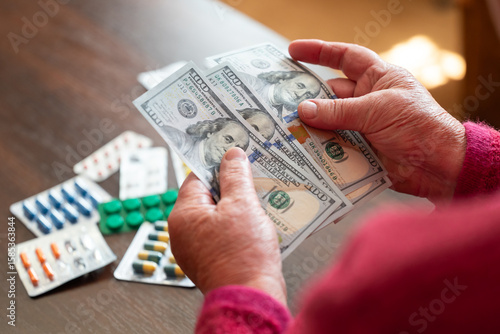 Senior woman counting dollars next to pills. Elderly woman holding US dollars after medicine purchase, highlighting high drug prices in USA