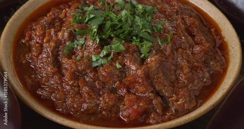 Grilled eggplant and tomato salad (Moroccan zaalouk) in a bowl. Fresh eggplants on the side. Zooming while rotating.