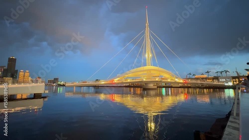 The stunning Cijin Rainbow Arch Bridge in Kaohsiung, Taiwan, is beautifully illuminated at dusk on June 28, 2025, with its reflection shimmering on the calm water, creating a captivating nightscape.
