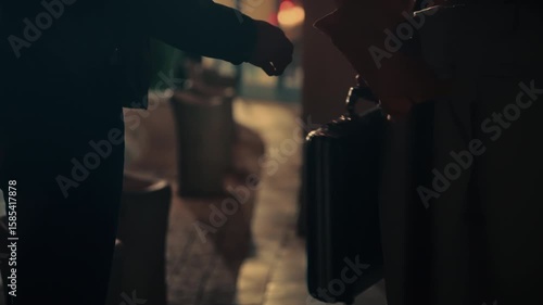 Briefcase exchange between two people in low light. Suspenseful, covert transaction perfect for spy thriller, crime drama, espionage, secret deal, or noir-style footage. undercover agents work.