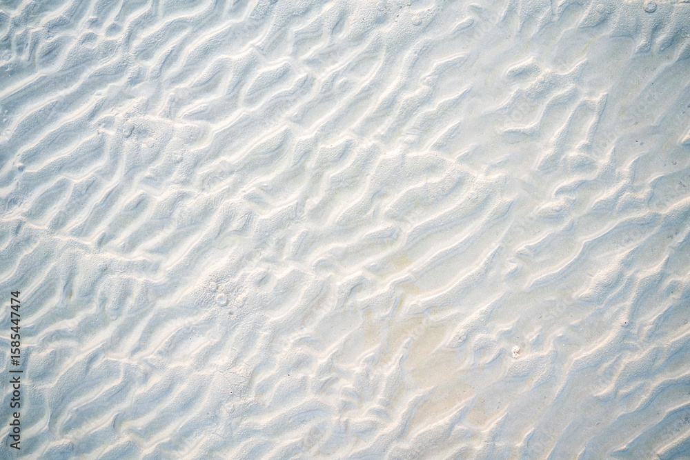 Obraz premium Close-up of beach sand texture with natural wave-like patterns and subtle shadows. Perfect background for summer, vacation, and nature-themed designs or creative projects.