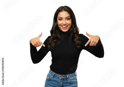 A smiling young woman with long dark hair points down with both thumbs, wearing a black turtleneck and jeans, isolated on a transparent background