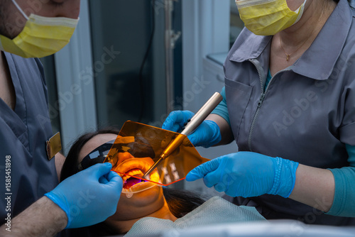 Dental professionals performing a treatment in a modern dental clinic with advanced equipment, ensuring patient comfort and safety during oral procedures.