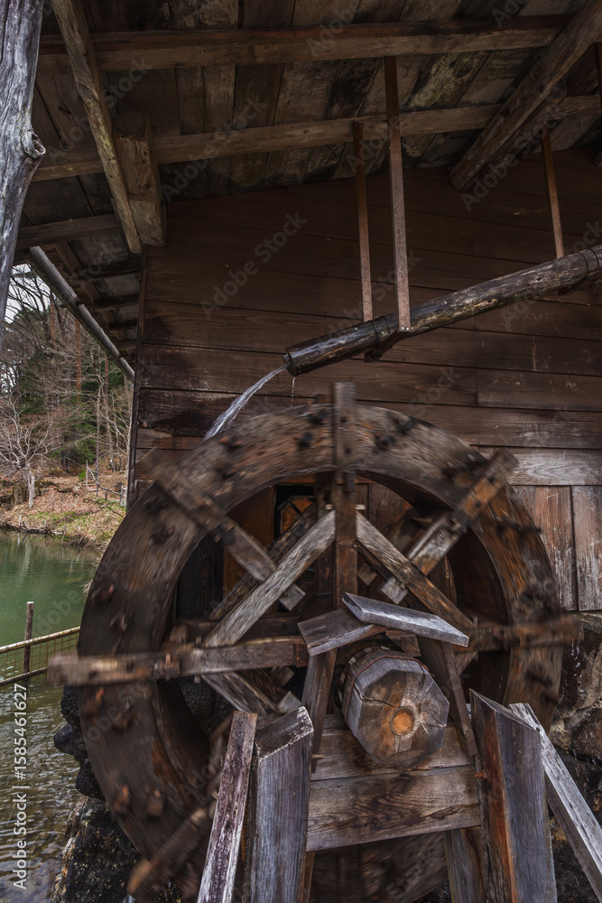 Antique wooden water wheel in motion, powered by a stream. The old mill shows signs of age and rustic charm. Located in Japan's scenic countryside, it offers a glimpse into history. Antique wooden water wheel in motion, powered by a stream. The old mill shows signs of age and rustic charm. Located in Japan's scenic countryside, it offers a glimpse into history.