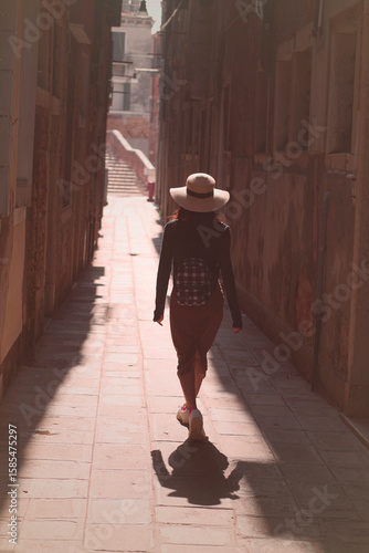 Woman in her 30s walking alone with confidence during the day through the alleys of Venice