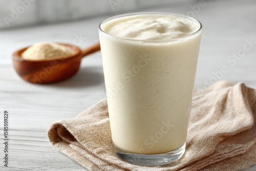 Glass of vanilla protein shake with powder in a wooden spoon. For healthy breakfast, sport nutrition and dietary supplement concept.