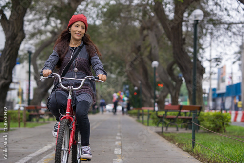 Young woman riding a bicycle through the city park on a cloudy day
