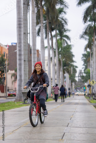 Young woman riding a bicycle through the city park on a cloudy day
