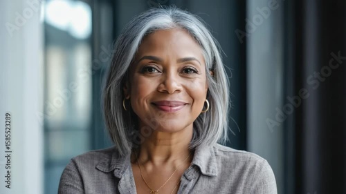 Mature woman with short grey hair and smile looking at camera in a professional setting.